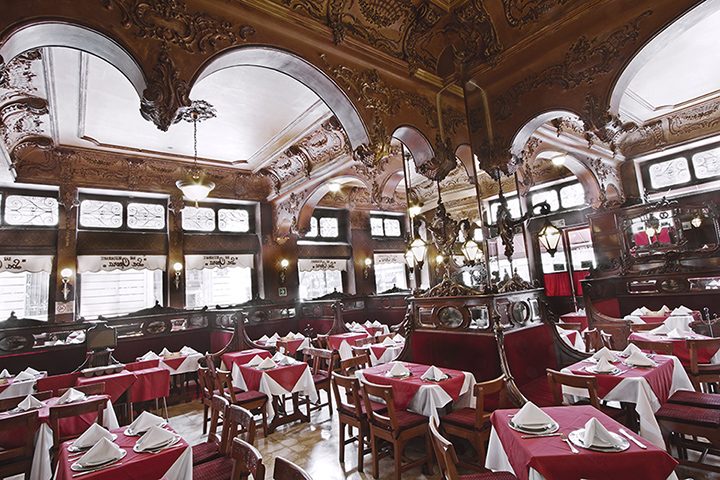 Salón principal con techo abovedado de yesería labrada y mesas vestidas de guinda y blanco